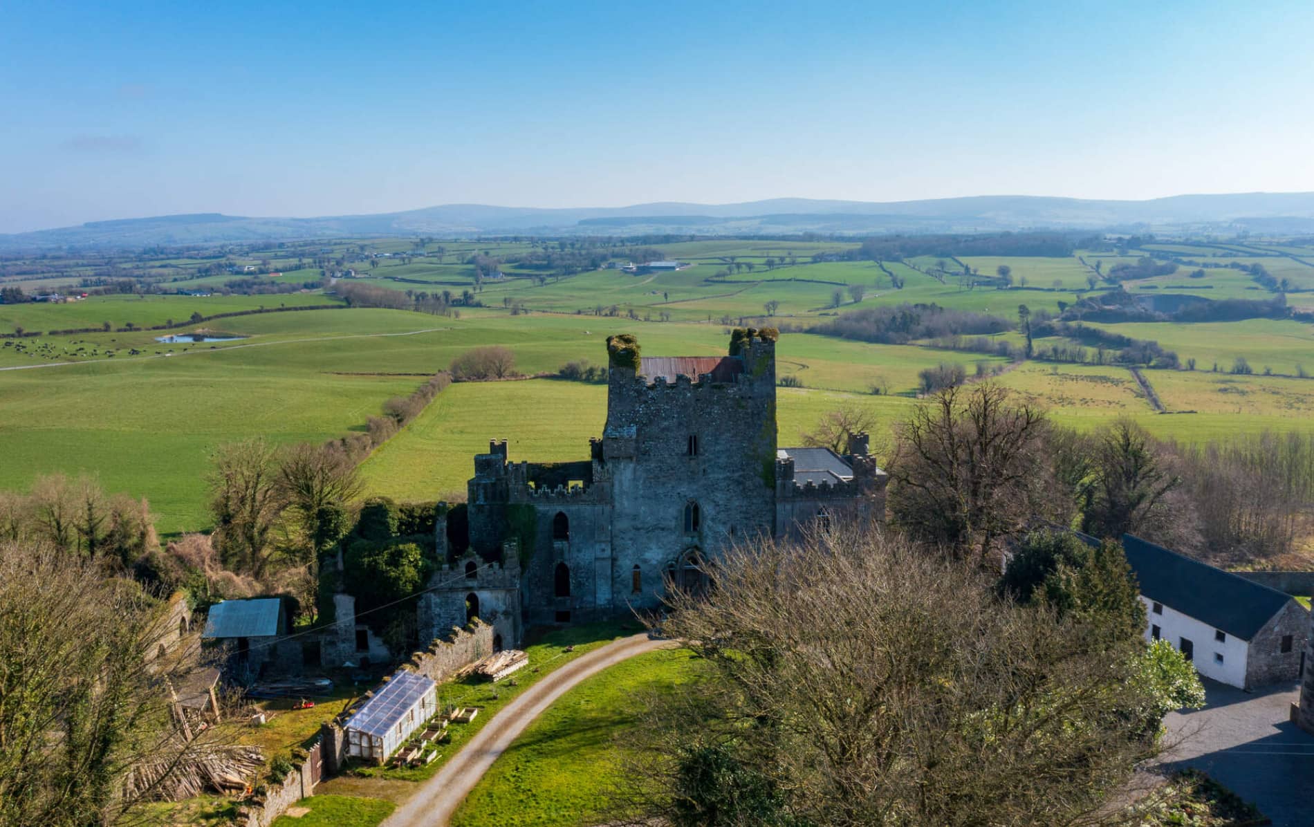 Aerial view of Leap Castle ruins in County Offaly surrounded by green fields and farmland.