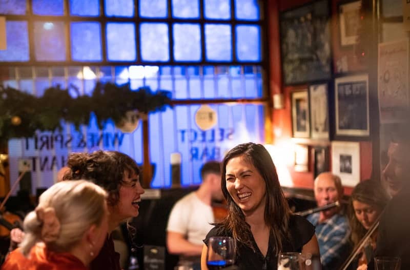 Inmitten von weihnachtlichem Grün und warmem Lichterglanz genießen die Besucher Musik und fröhliche Stimmung in Smithfield, wo das Twinkletown-Weihnachtserlebnis stattfindet.