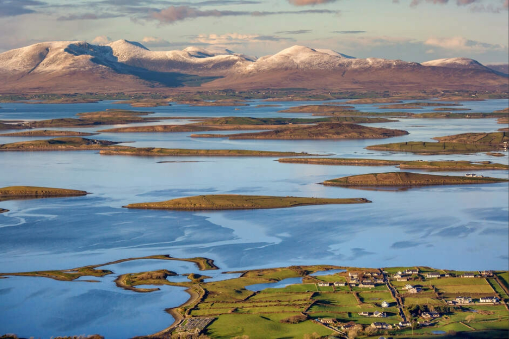 Panoramic view of Clew Bay in County Mayo, with its many islands, green fields and snow-capped mountains in the distance.