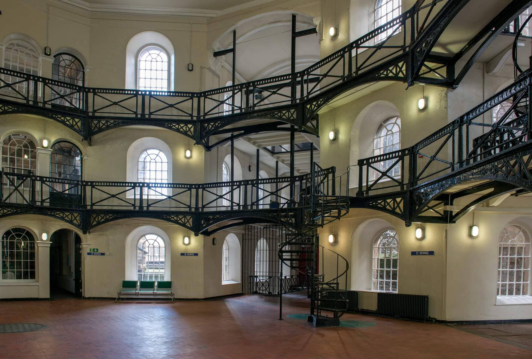 Interior of Crumlin Road Gaol in Belfast, with iron walkways, barred windows and spiral staircase.