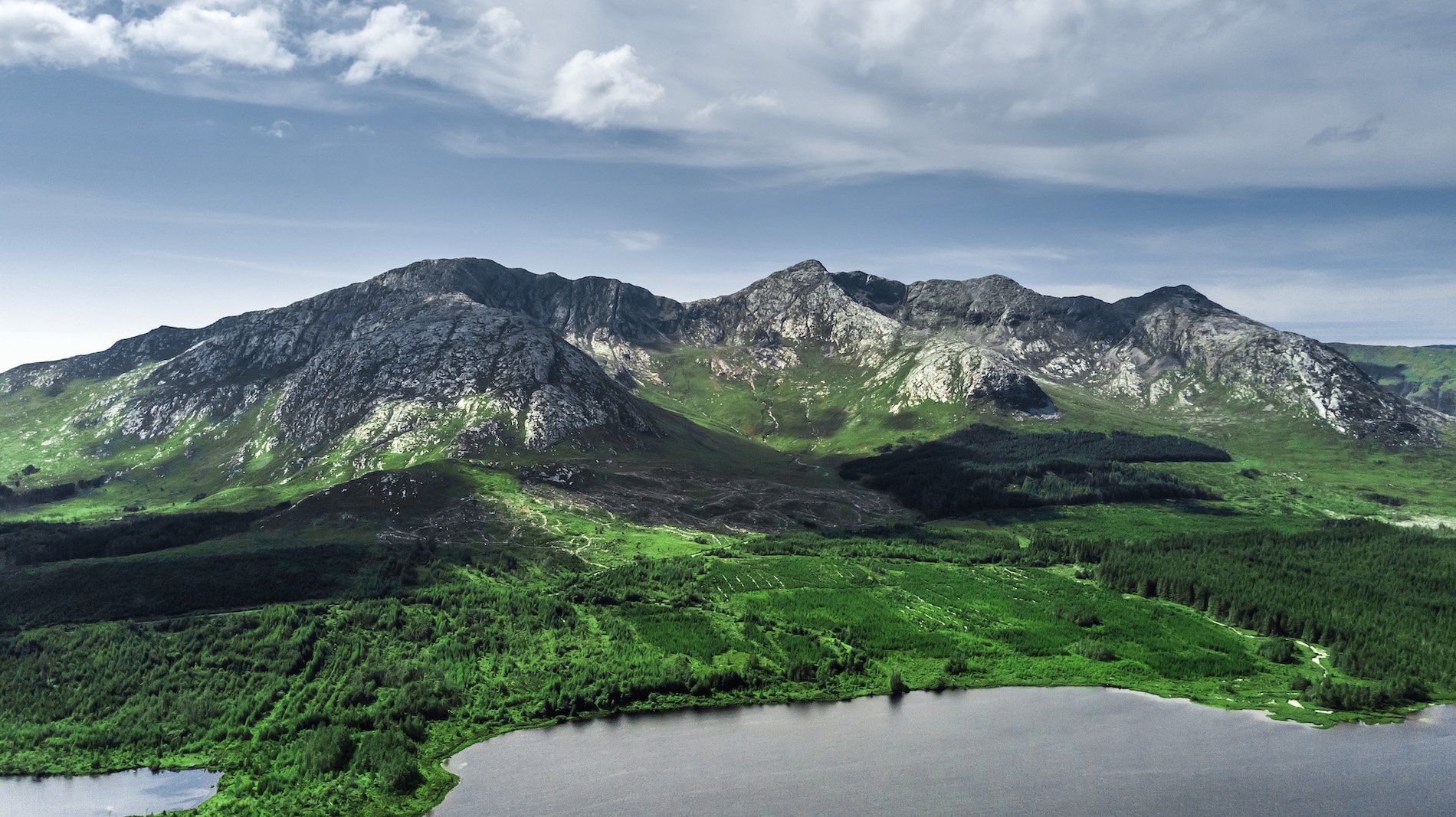 Scenic view of the Twelve Bens mountain range and green landscape in Connemara, County Galway.
