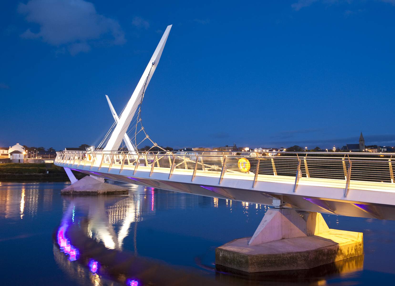 Le Peace Bridge à Derry~Londonderry illuminé la nuit, se reflétant dans la rivière Foyle pendant la Saint Patrick.