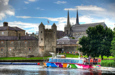 Un bateau de croisière coloré sur la rivière Erne à Enniskillen, avec la cathédrale Saint-Macartin en arrière-plan.