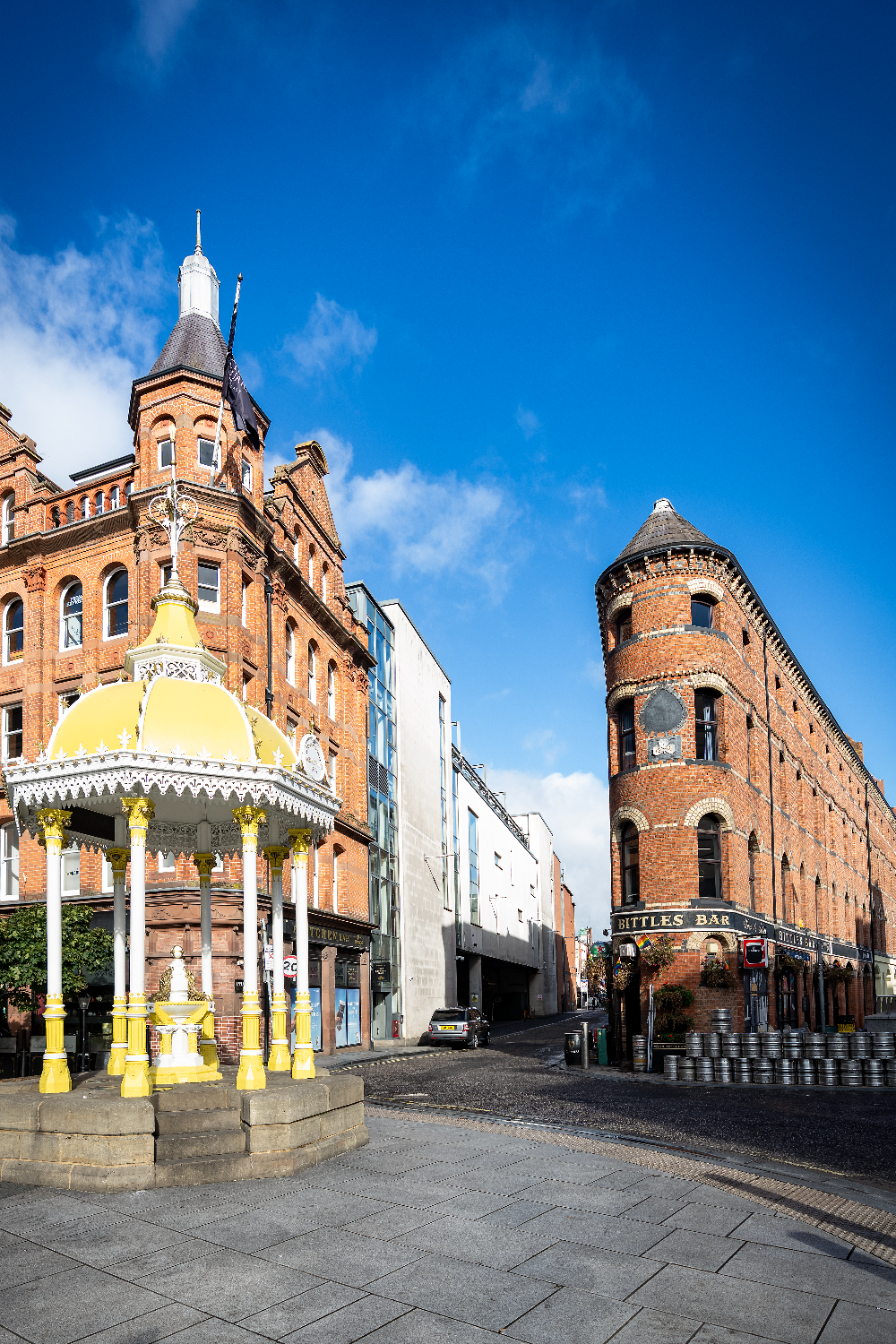 Bittles Bar in Belfast, a distinctive red-brick flatiron building beside the ornate Jaffe Memorial Fountain.