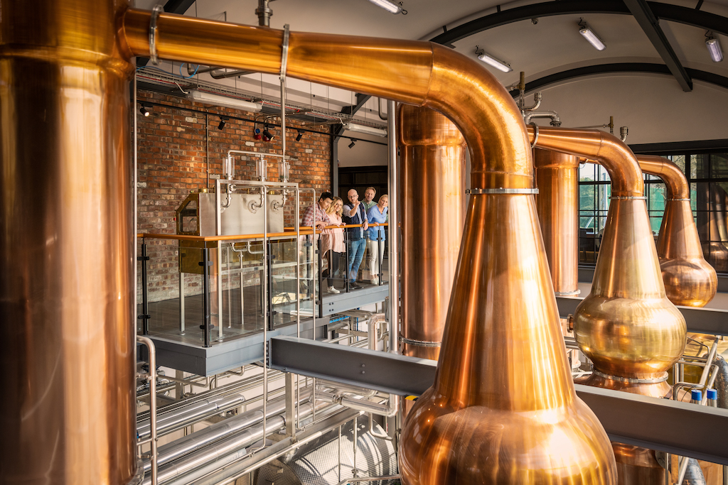 Visitors viewing copper pot stills during a guided tour at Hinch Distillery, County Down.