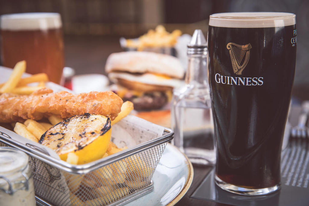 Fish and chips with grilled lemon beside a pint of Guinness and a burger at the Titanic Hotel Belfast.