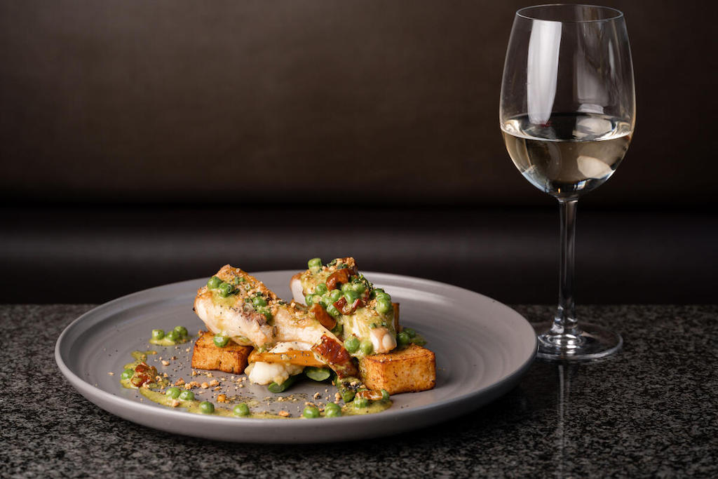 Grilled fish with peas and potatoes served with a glass of white wine at the Europa Hotel, Belfast.