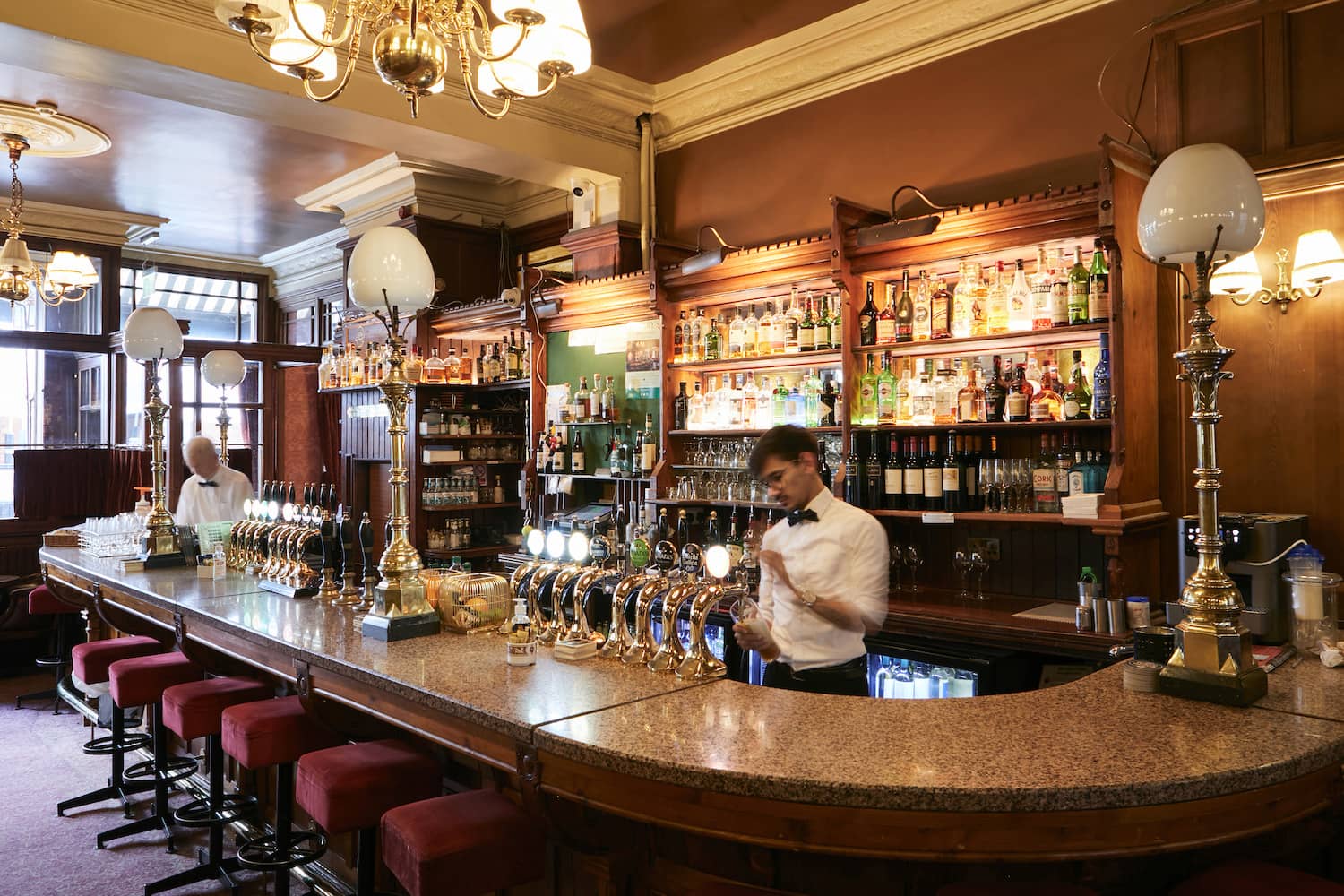 Innenraum eines traditionellen irischen Pubs mit klassischer Holzbar und Barkeepern in Dublin.