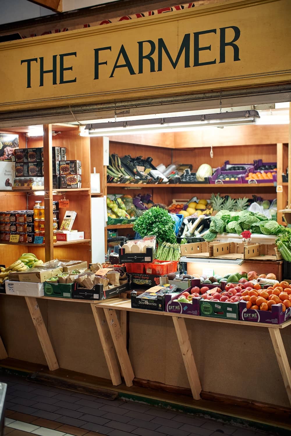 A colourful fruit and vegetable stall beneath a sign reading “The Farmer” at Cork’s English Market.