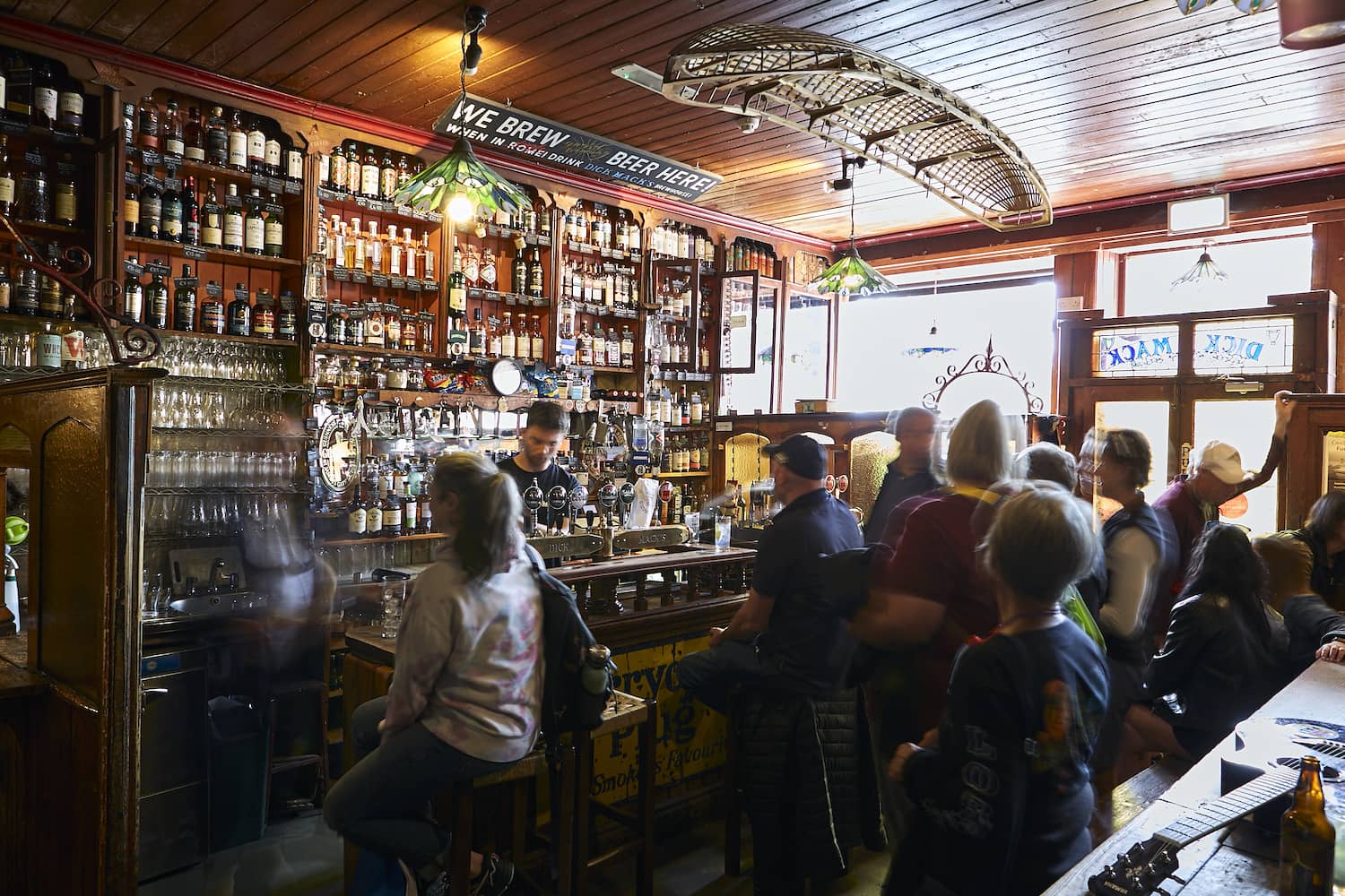 A lively traditional pub interior in Dingle, County Kerry, with customers gathered around the bar.