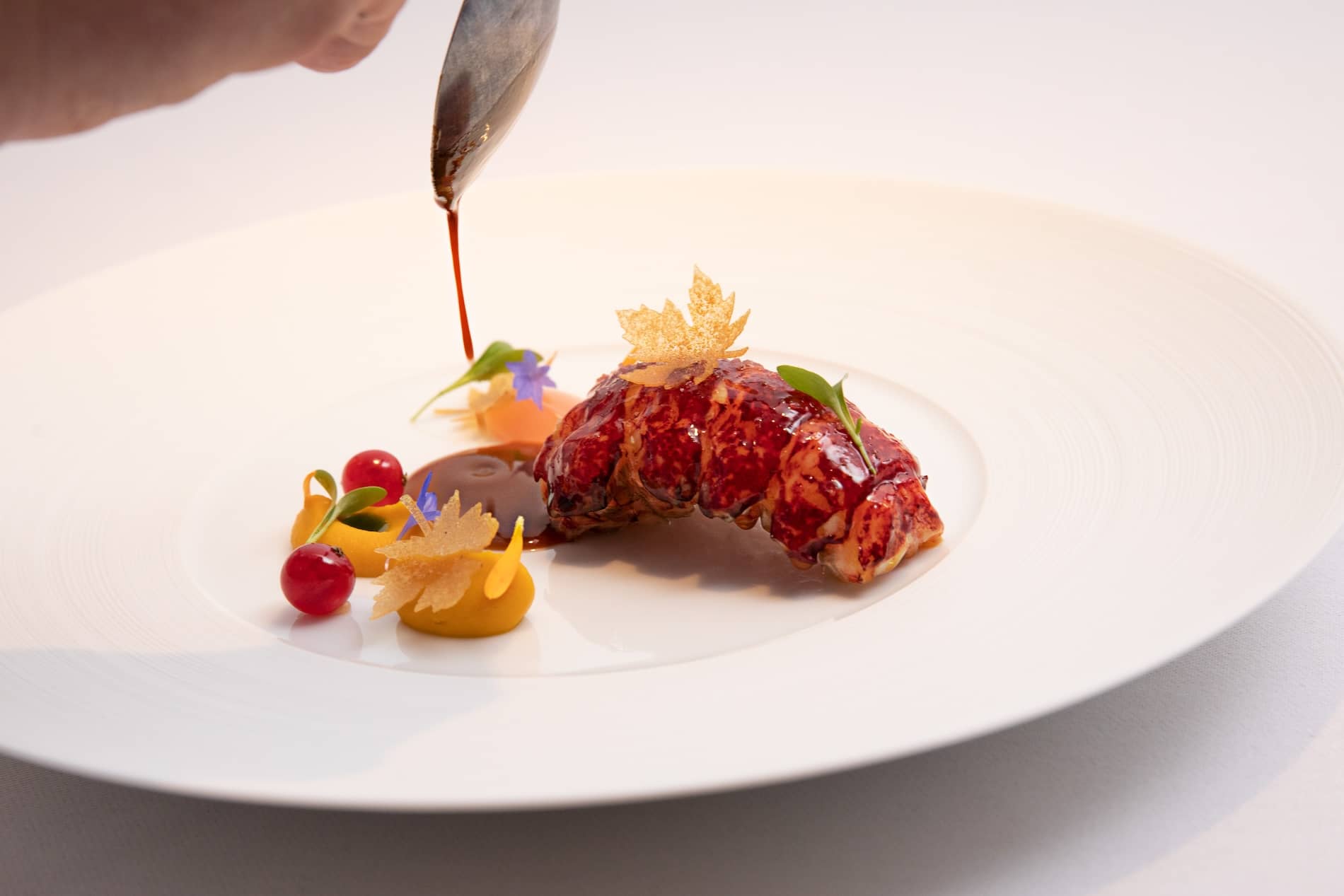 Sauce being poured over an elegant lobster dish with colourful garnishes at Chapter One, Dublin.