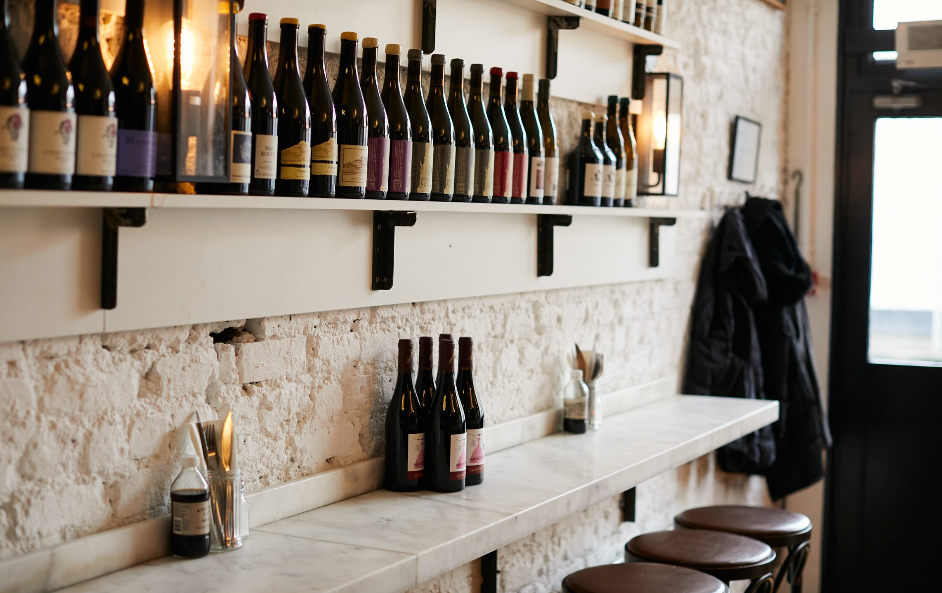 Wine bottles line shelves above a marble counter in the cosy interior of Fish Shop in Dublin.