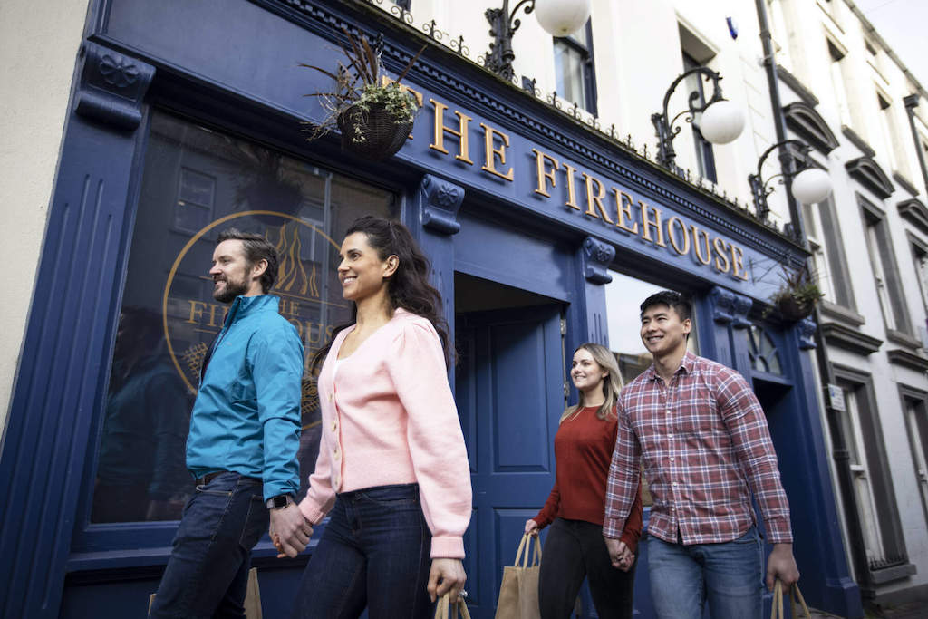 Deux couples se promènent main dans la main devant la façade bleue du bar grill The Firehouse à Enniskillen, dans le comté de Fermanagh.