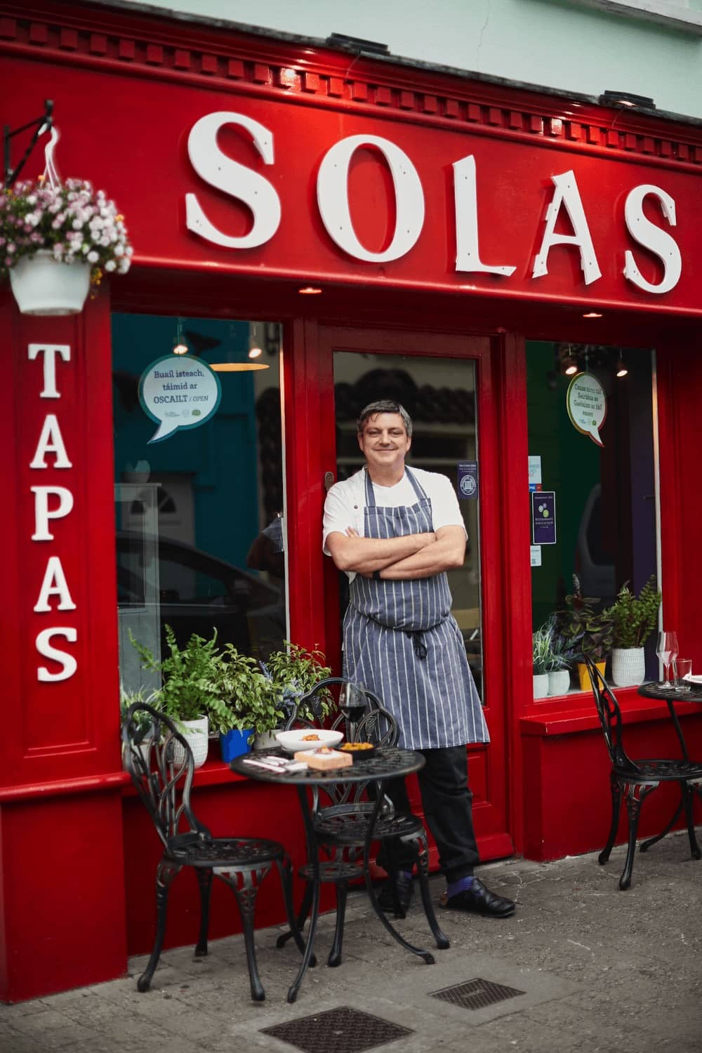Ein Koch vor dem leuchtend roten Solas Tapas-Restaurant in Dingle, Grafschaft Kerry.