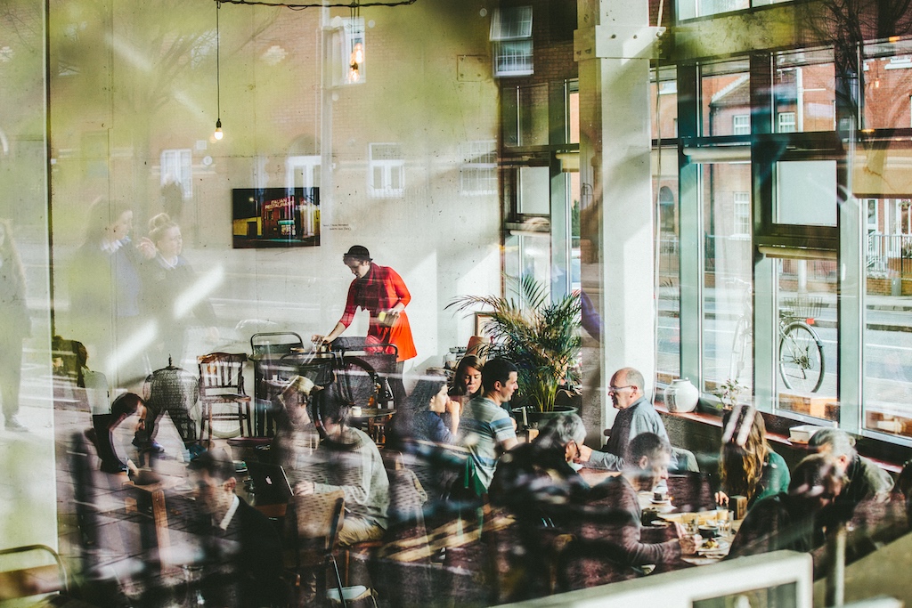 Diners inside The Fumbally café in Dublin City, viewed through a window.