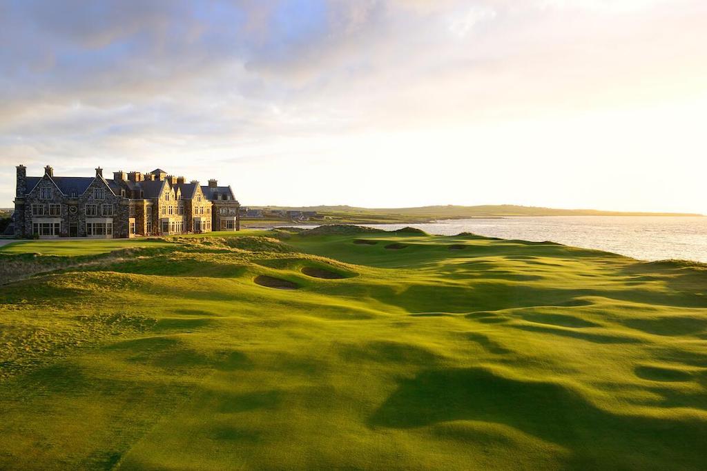 Luxury clubhouse overlooking Trump Doonbeg Golf Links in County Clare at sunset, with rolling dunes beside the sea.