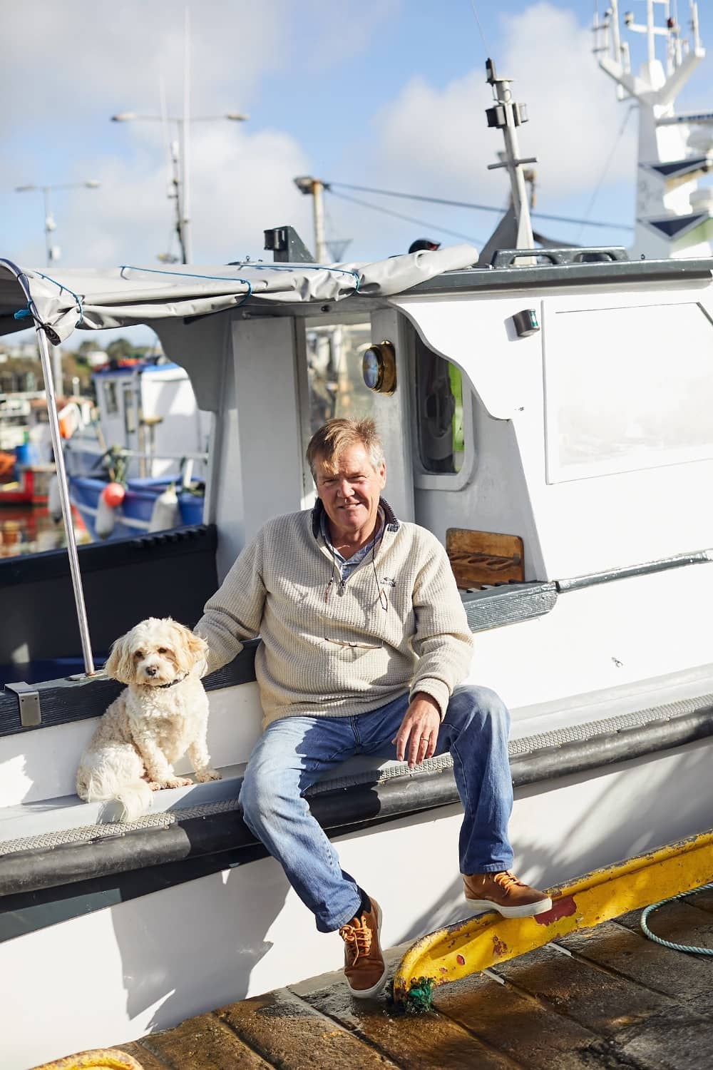 Brian Roberts with his dog Alfie at the helm of a boat on Kinsale Harbour, County Cork.