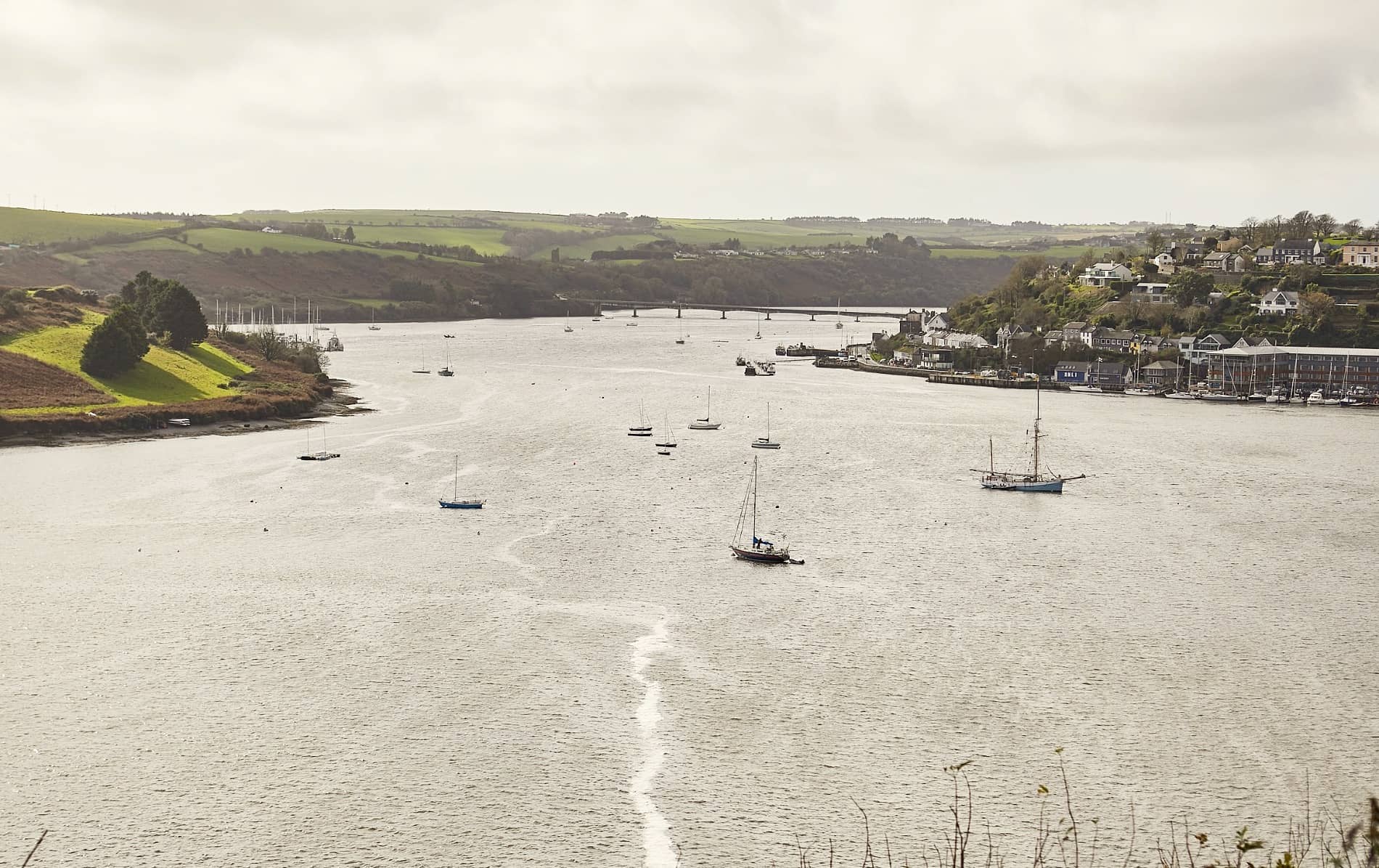 Sailboats moored in Kinsale Harbour with rolling green hills in the background, County Cork.