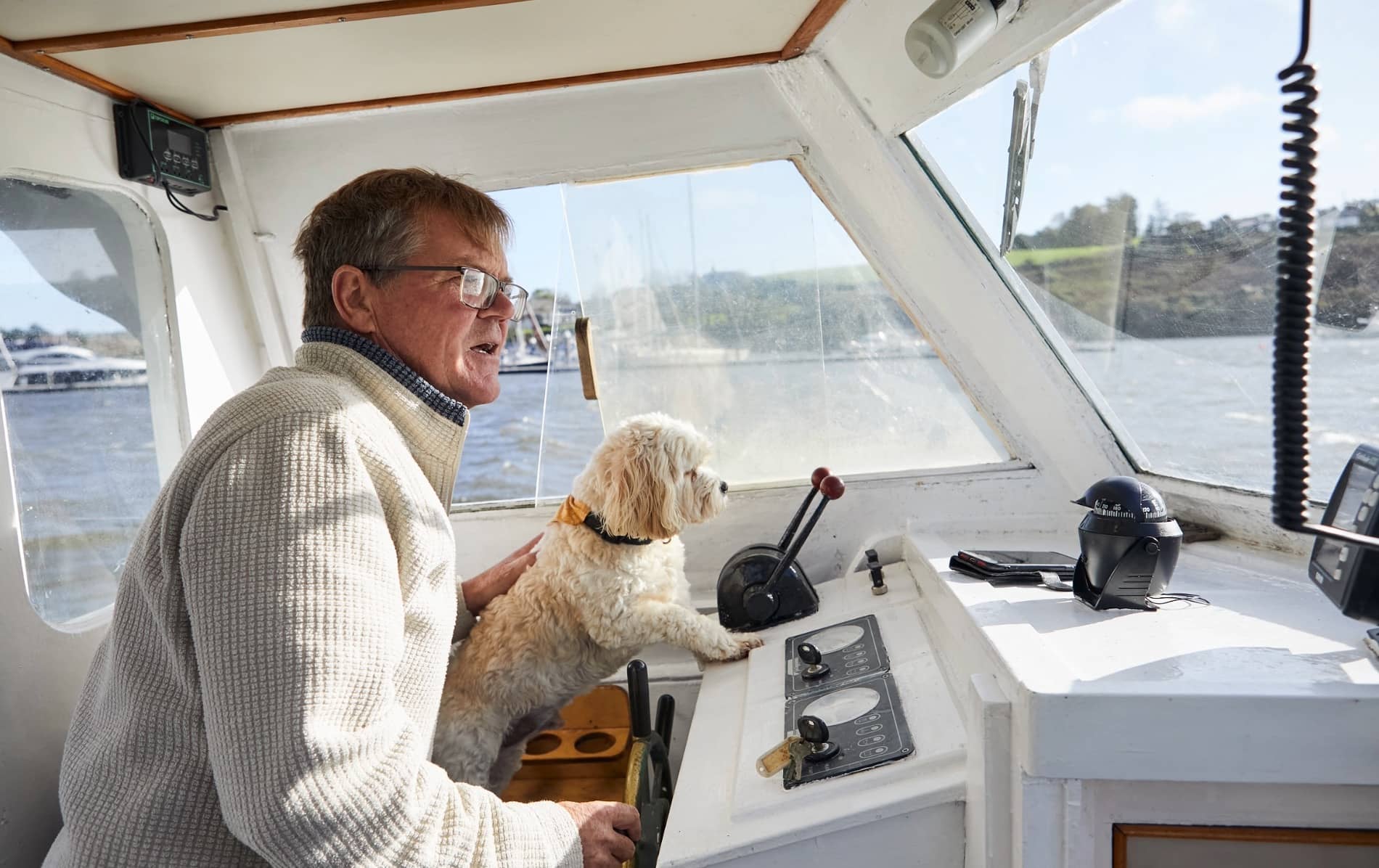 Brian Roberts sitting on his boat with his dog Alfie at the harbour in Kinsale, Ireland.