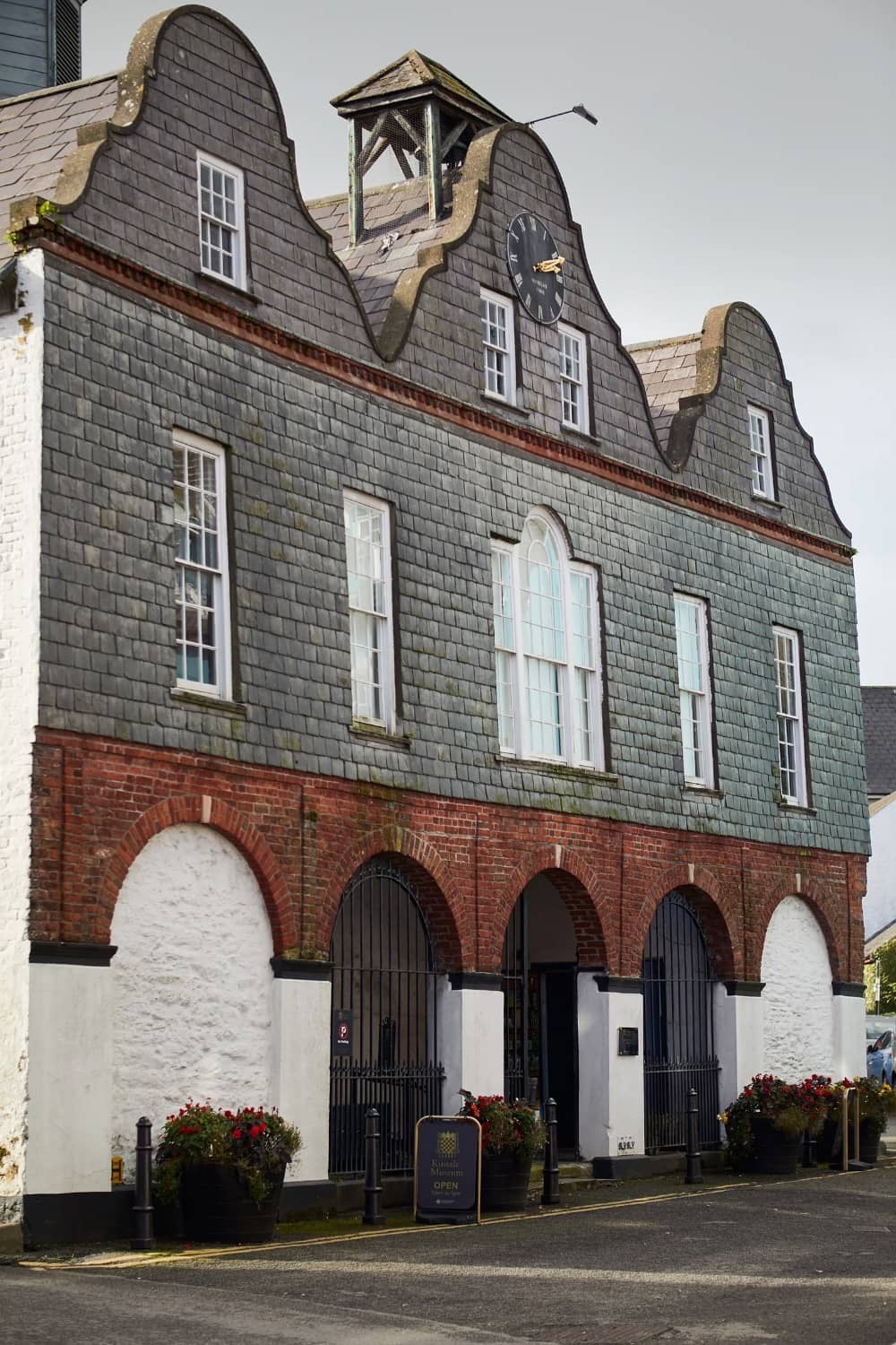 Historic building housing Kinsale Museum, featuring arched entrances, clock tower, and grey slate façade.