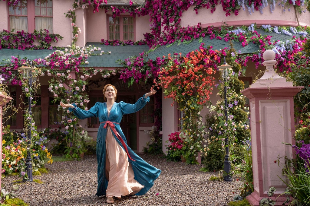 Amy Adams in einem fließenden Kleid vor einem mit Blumen bedeckten rosa Haus in der Grafschaft Wicklow während der Dreharbeiten zu Disenchanted.