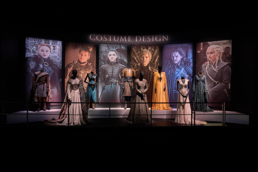 Game of Thrones® costume display with mannequins and character portraits at the Game of Thrones® Studio Tour.