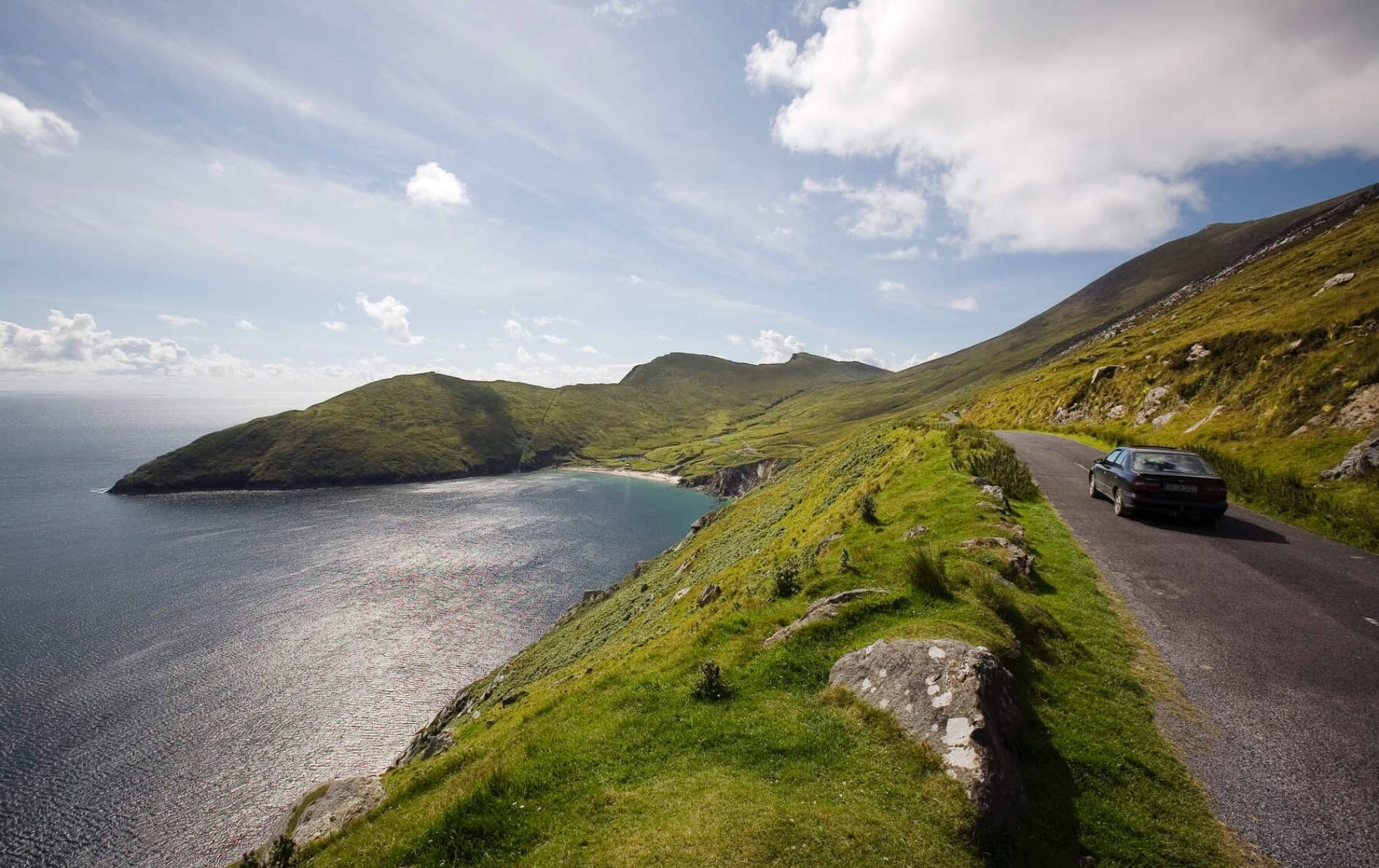 Scenic cliffside road with a car overlooking Keem Bay’s turquoise waters on Achill Island, County Mayo.