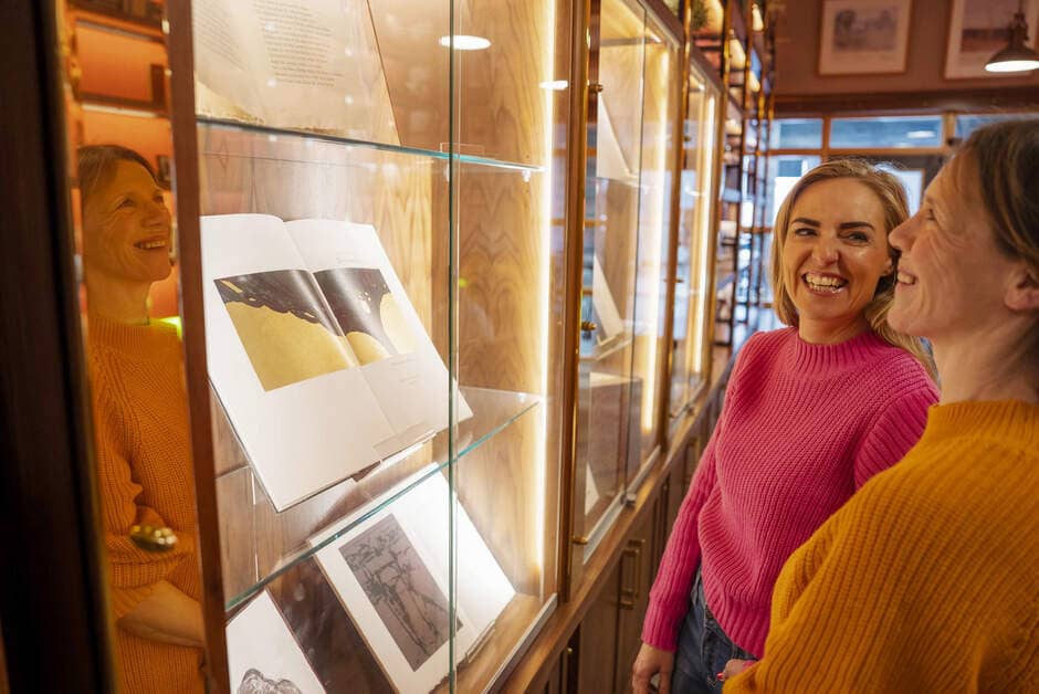 Two women smiling as they view literary exhibits at Seamus Heaney HomePlace in Bellaghy, County Londonderry.