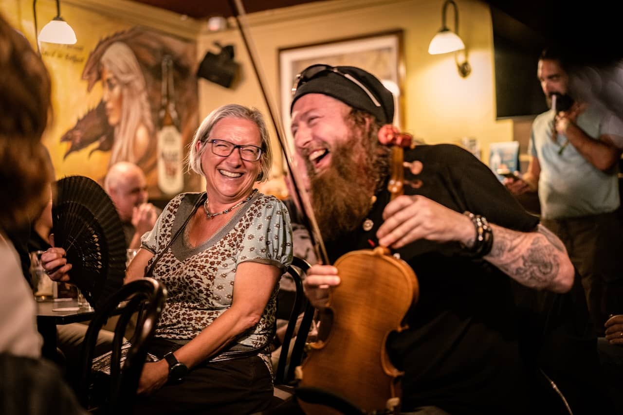 Een traditionele muzikant vermaakt de bezoekers tijdens een levendige Ierse muzieksessie in McHugh's pub in Belfast.
