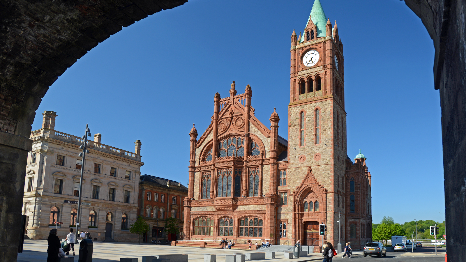 La Guildhall di Derry~Londonderry con la sua torre dell'orologio, incorniciata da edifici storici, in una giornata di sole.