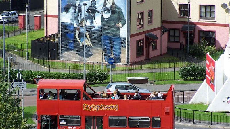 Un bus turistico passa davanti a un grande murale nel Bogside a Derry~Londonderry.