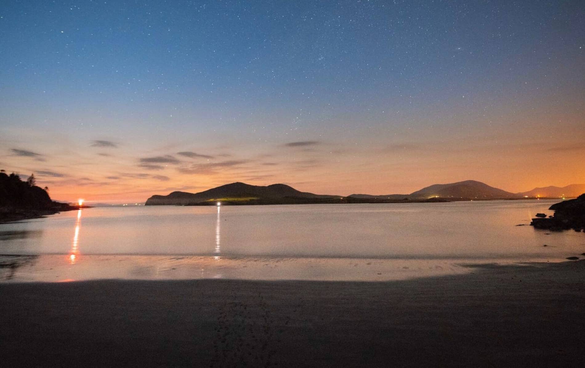 Una tranquila vista nocturna sobre Kerry International Dark Sky Reserve con un cielo lleno de estrellas reflejándose en aguas tranquilas.