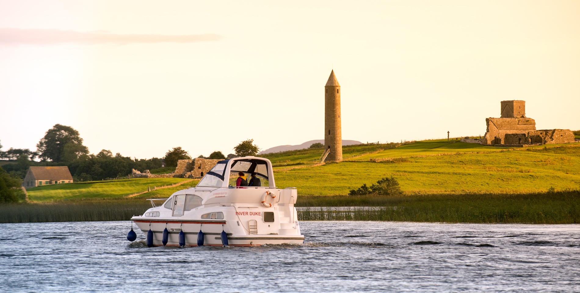 Cruiser on Lower Lough Erne passing Devenish Island’s round tower and monastic ruins.