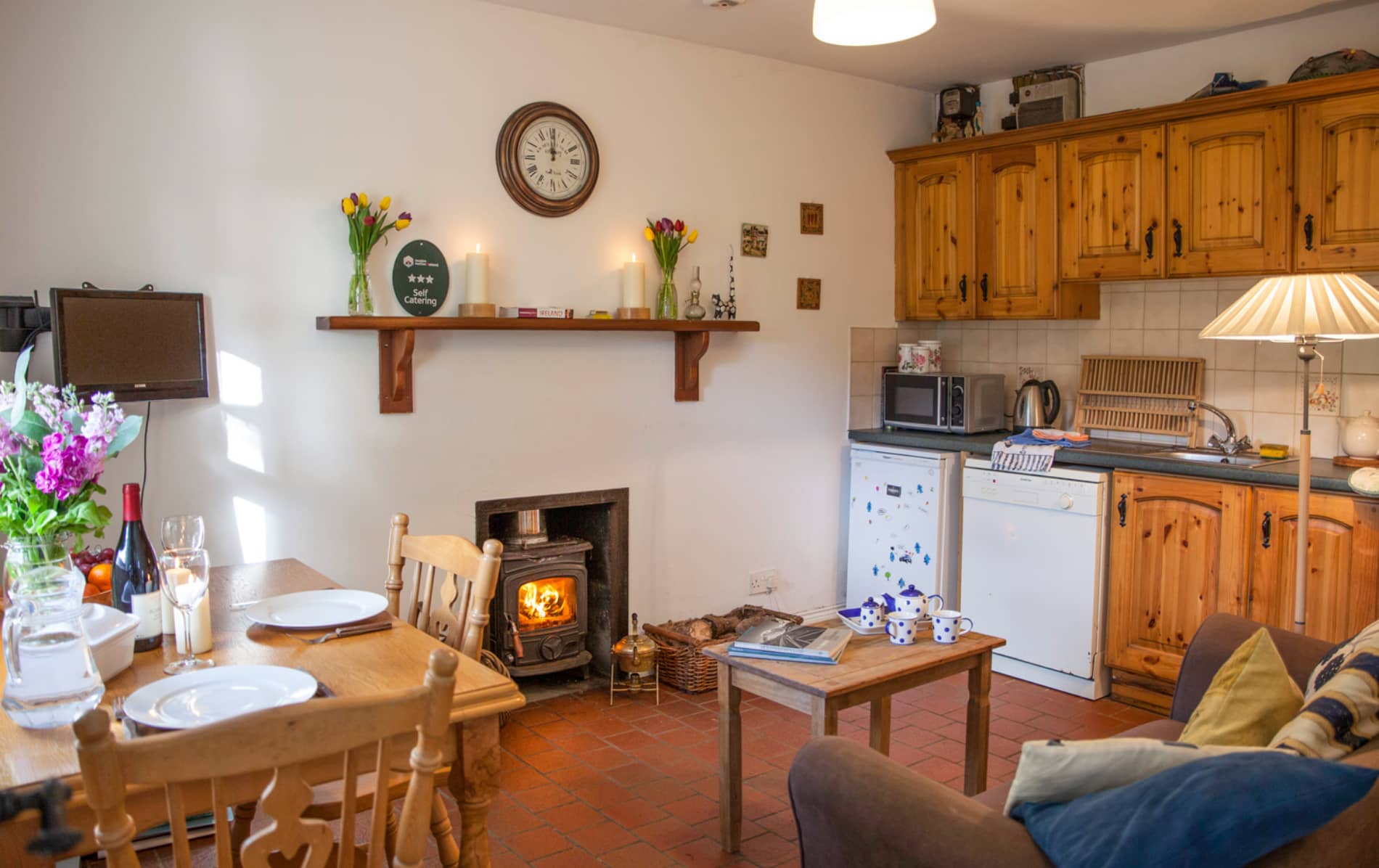 Cosy self-catering kitchen with pine cabinets, wood stove and dining table in Mr McGregor's Cottage, County Tyrone.