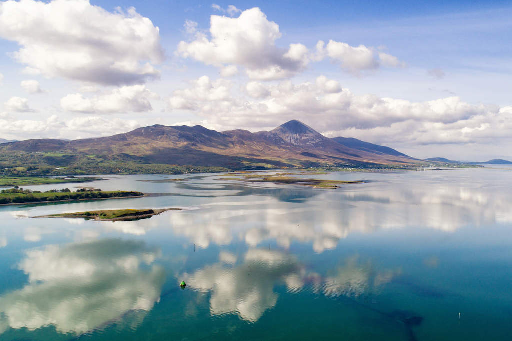 Calm water reflecting clouds and Croagh Patrick, with the coast stretching toward Achill Island.