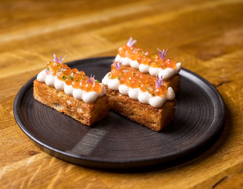 Plated starter at Éan, Galway: toasted brioche topped with whipped cheese, salmon roe and edible flowers.