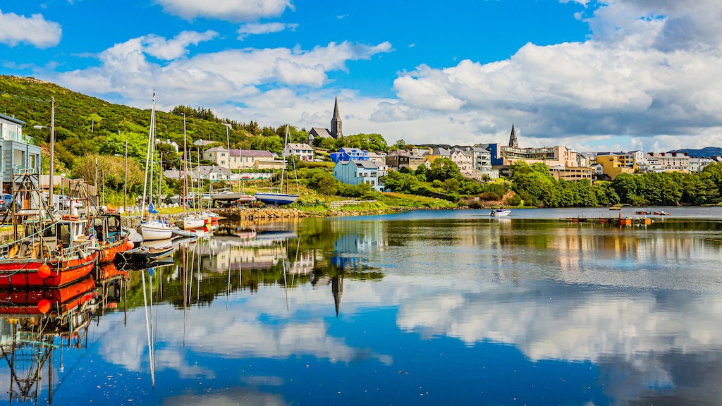 Fishing boats and yachts moored at Clifden harbour with the town rising on the hillside.