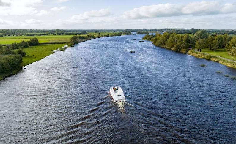 Aerial view of green fields and waterways near Banagher featuring Silverline Cruises boat on the water.
