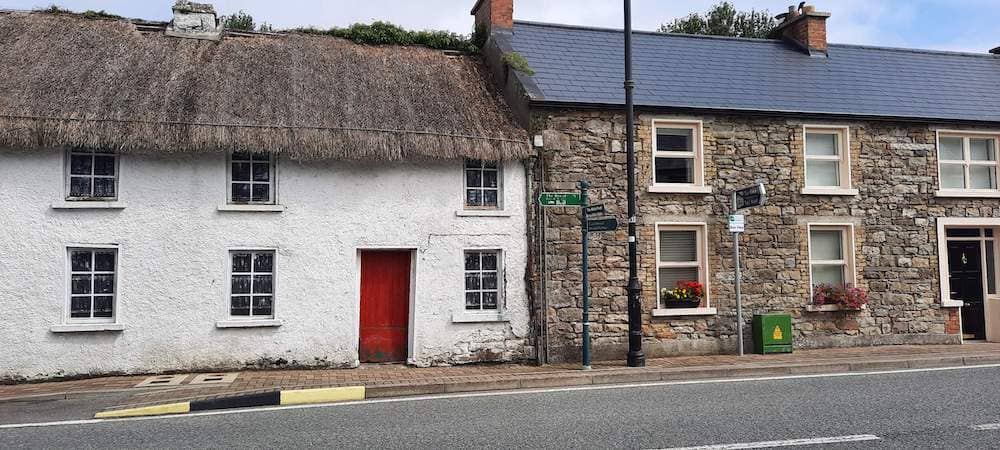 Thatched whitewashed cottage beside a stone house in the heart of Drumod village, County Leitrim.