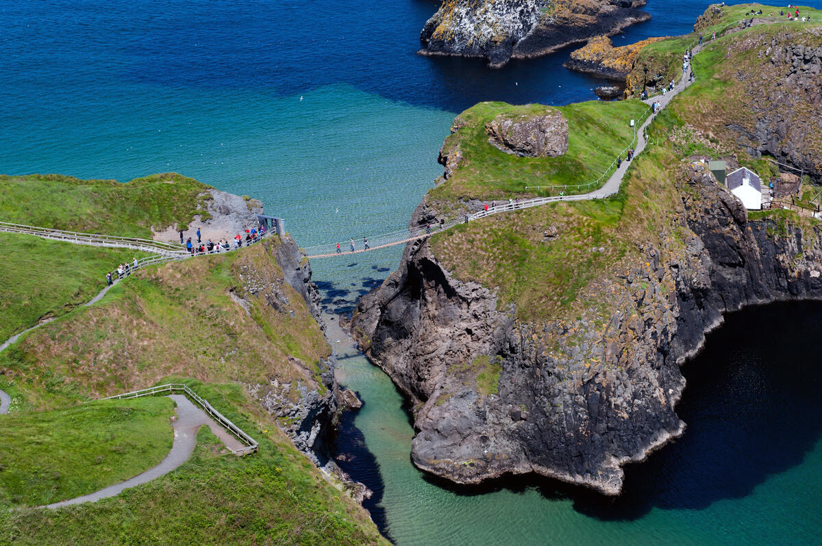 Bezoekers die de Carrick-a-Rede touwbrug boven de zee oversteken op de Causeway kustroute, county Antrim.