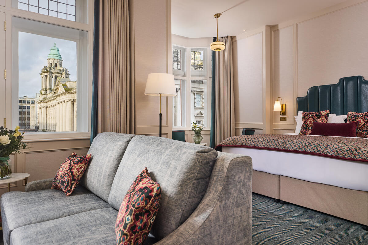 Een elegante hotelkamer in The Bedford Hotel Belfast, met uitzicht op het stadhuis van Belfast vanuit het raam.