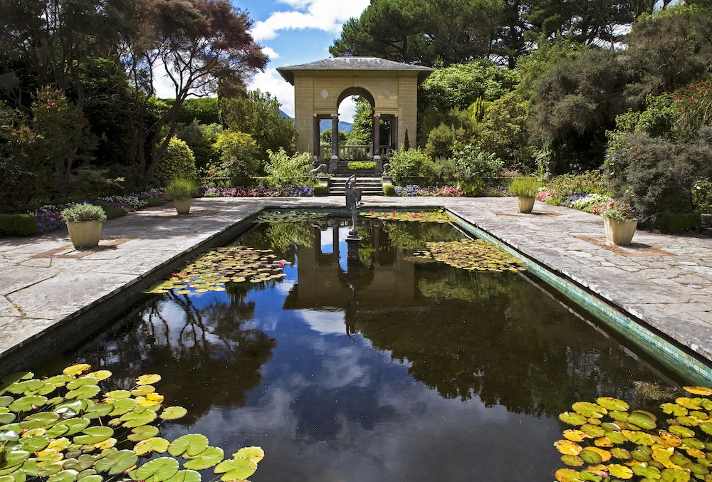 Italian Garden at Garnish Island with reflecting pool, lily pads and classical pavilion surrounded by lush planting.