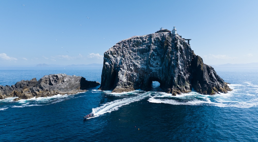 Fast boat approaching the lighthouse on Fastnet Rock off the coast of County Cork.