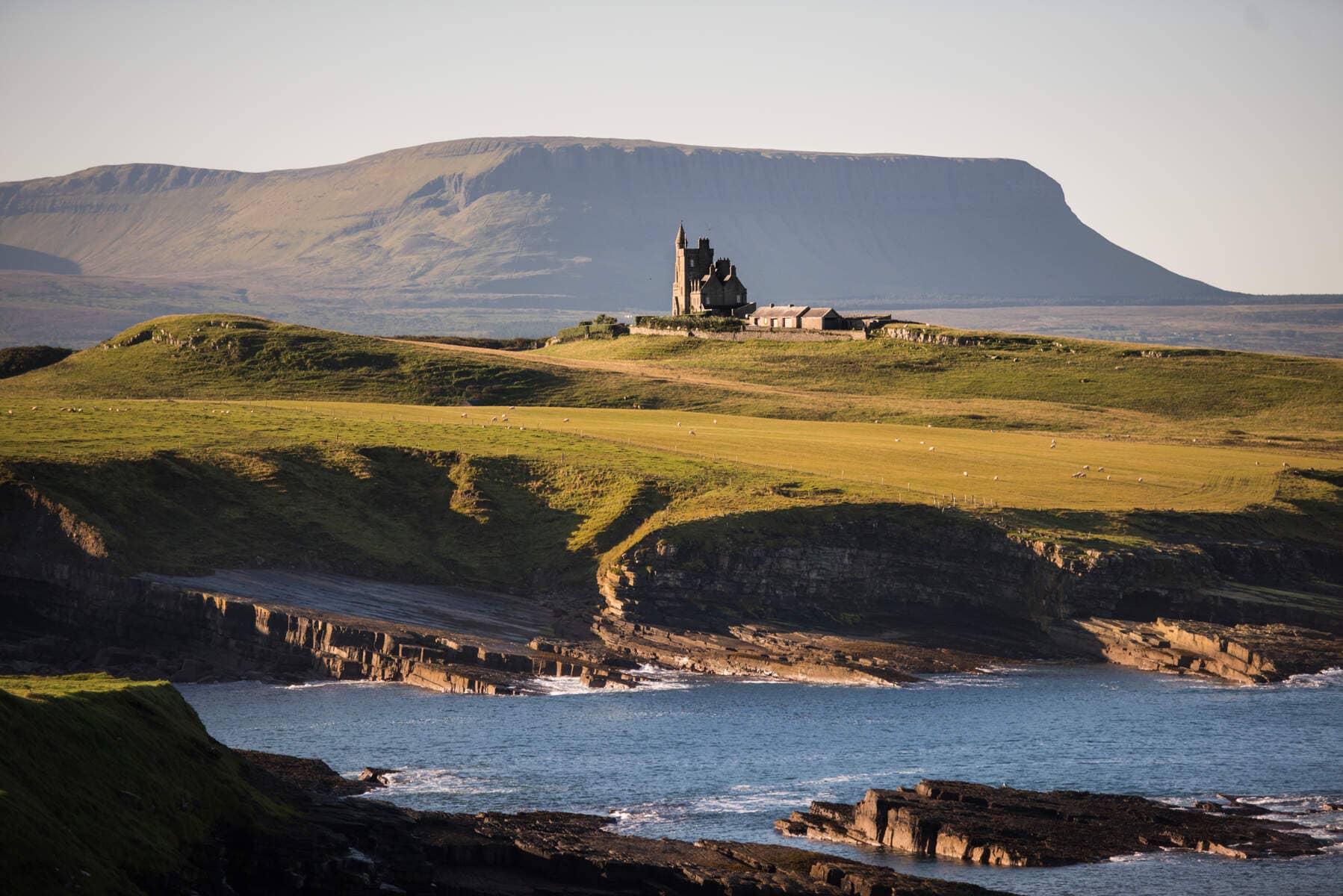 Classiebawn Castle op een groene kaap met uitzicht op de zee en Ben Bulben op de achtergrond, county Sligo.