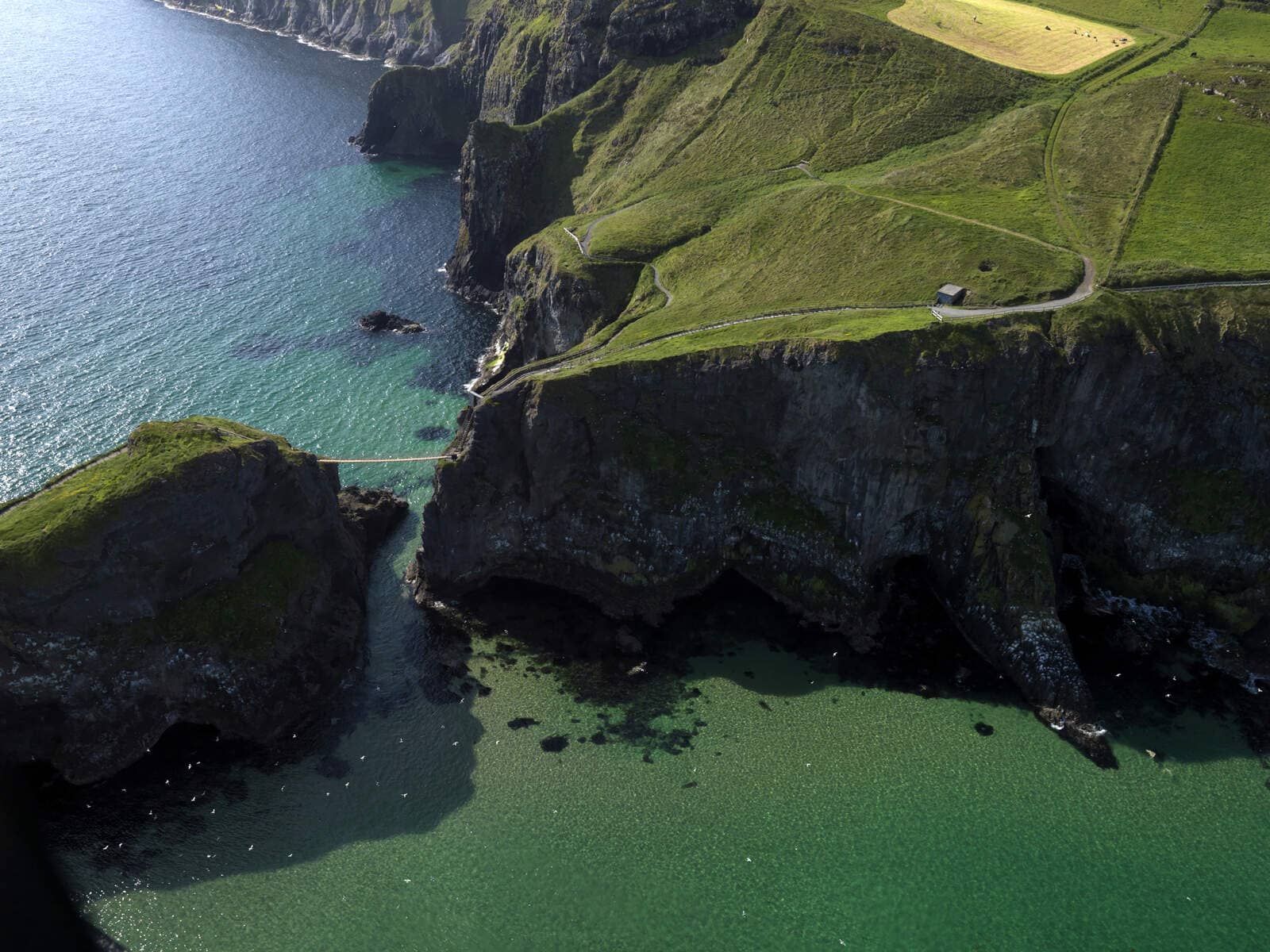Luchtfoto van de Carrick-a-Rede Rope Bridge over de kliffen en het turquoise water in county Antrim.
