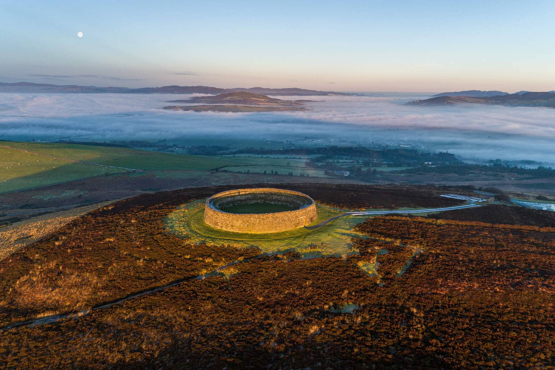 Luchtfoto van het ringfort An Grianán of Aileach bij zonsopgang, omgeven door mistige heuvels in county Donegal.