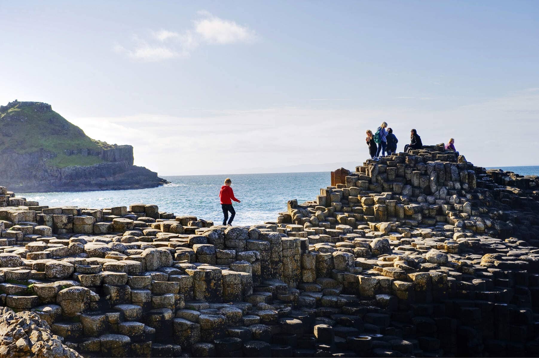 Toeristen verkennen de basaltzuilen bij de Giant's Causeway langs de kust van Antrim.