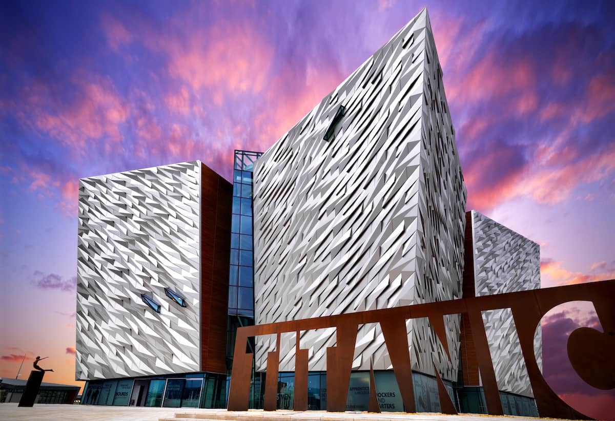 Das Titanic Belfast Museum mit seiner markanten, kantigen Fassade vor einem farbenfrohen Himmel bei Sonnenuntergang im Titanic Quarter von Belfast.