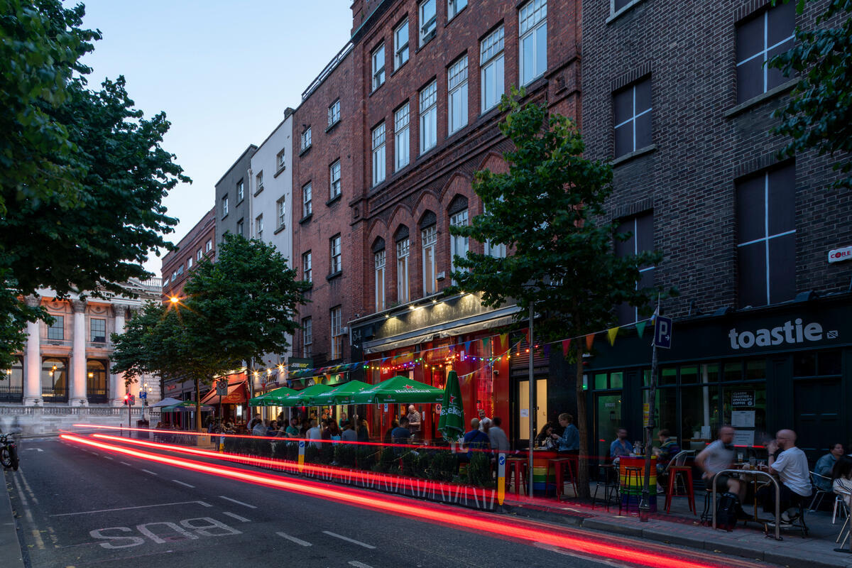 Abendstimmung in der Parliament Street in Dublin mit Außengastronomie und vom Verkehr erzeugten Lichtern.