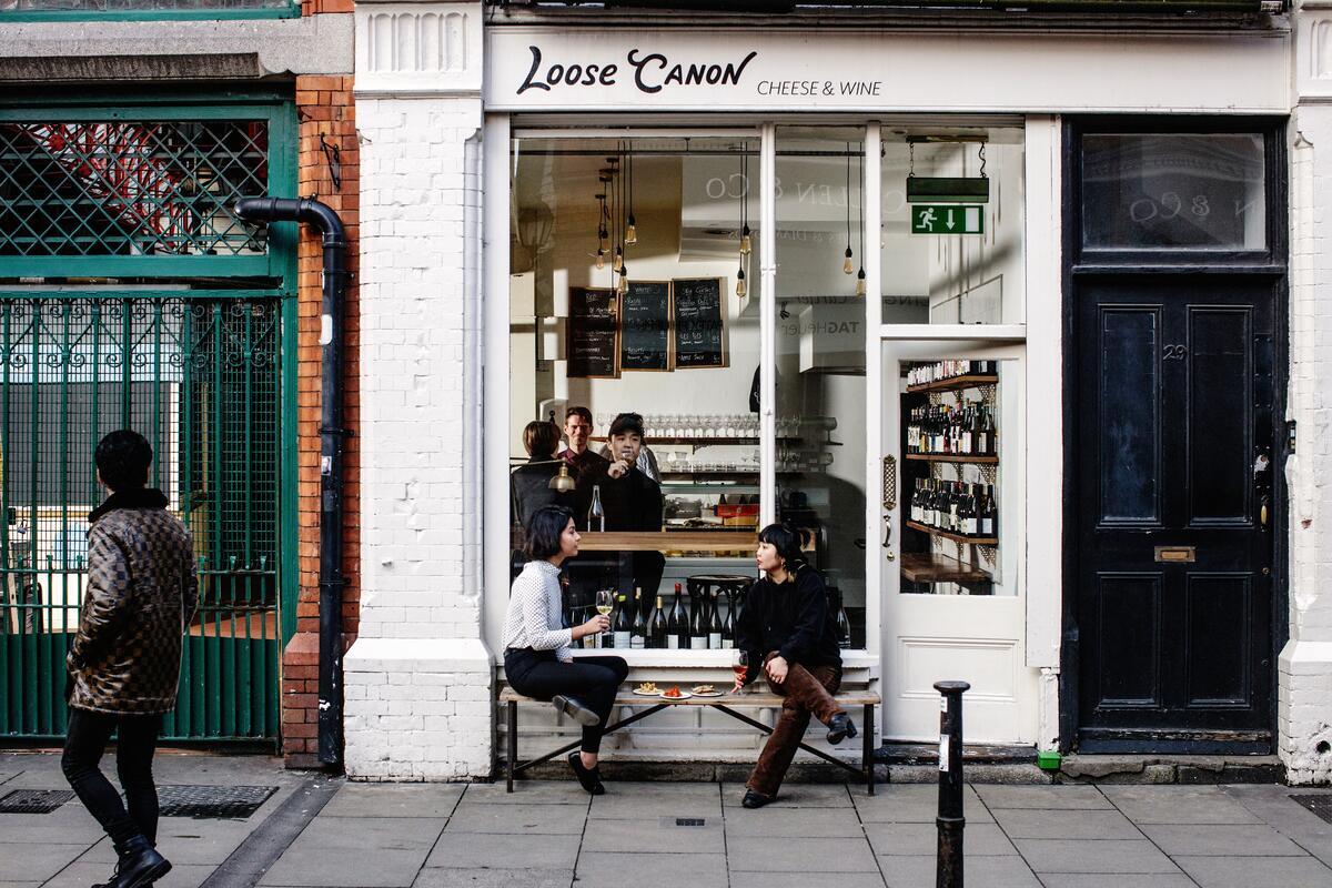 Außenansicht des Loose Canon, einem Käse- und Weinladen in Dublin, mit Menschen, die sich davor unterhalten.
